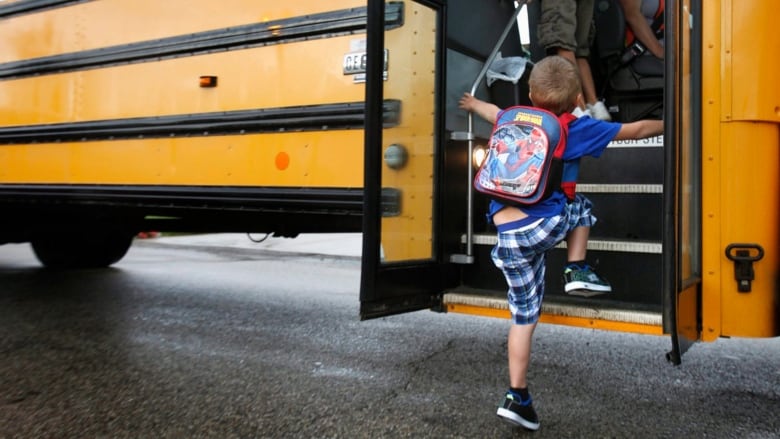 Kid with backpack gets on bus