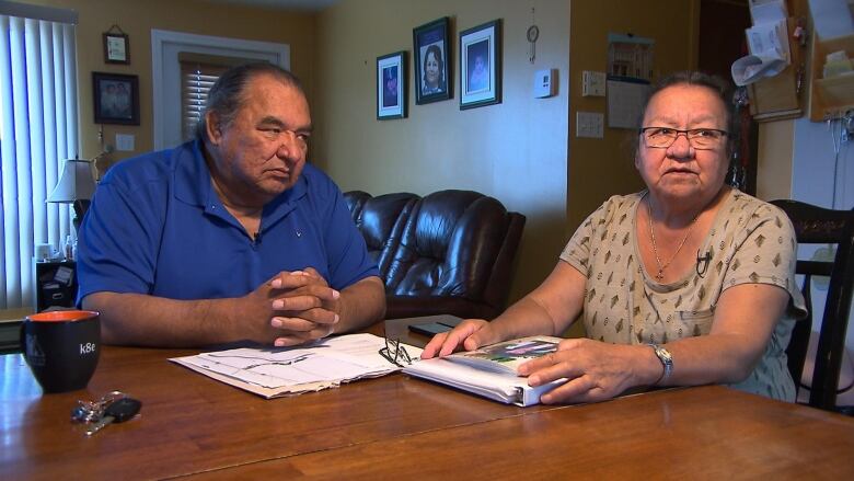 A couple sits at a table with paperwork in front of them 