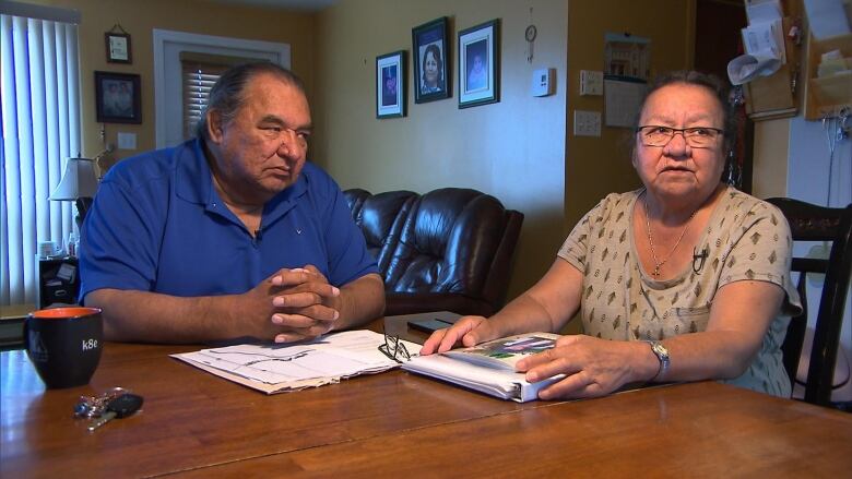 A couple sits at a table with paperwork in front of them 