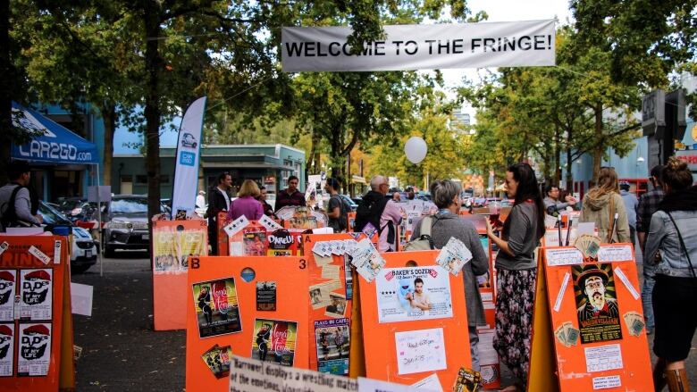 Theatregoers gather behind signs advertising shows.