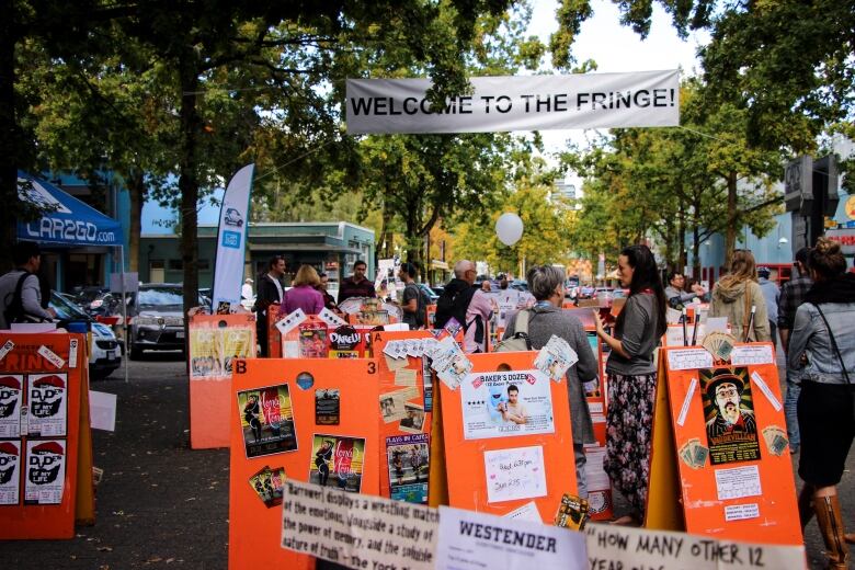 Theatregoers gather behind signs advertising shows.