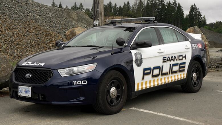 A black and white police car with the words Saanich POLICE in black on a white door.