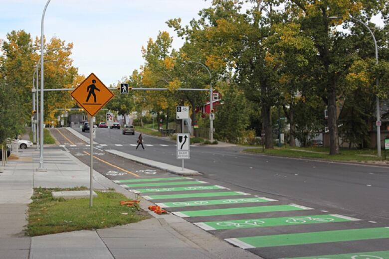 A cycle track is separated by a concrete median from the rest of the tree-lined roadway.