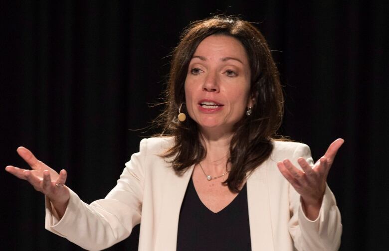 A woman with a microphone attachment gestures.