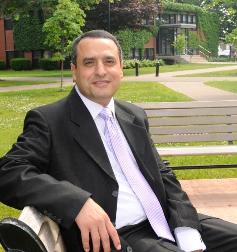 A man in a business suit sits on a bench.