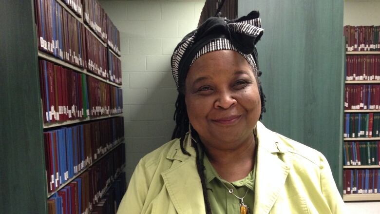 A Black woman in a library wearing a lime green jacket 