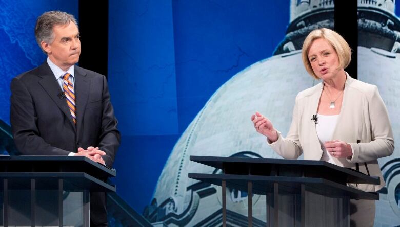 Jim Prentice looks on while Rachel Notley speaks.