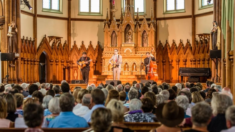 Three musicians perform while a large crowd listens at historic St. Mary's Church as part of the Under the Spire music festival. 