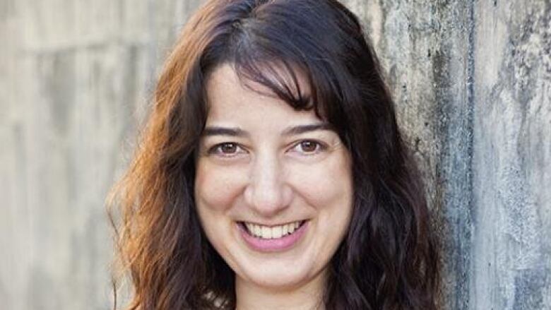 A woman with long dark hair smiling. 