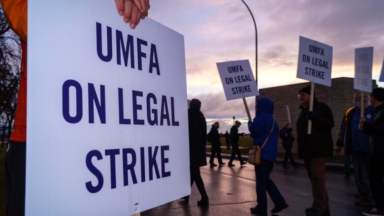 Picketers hold signs saying 