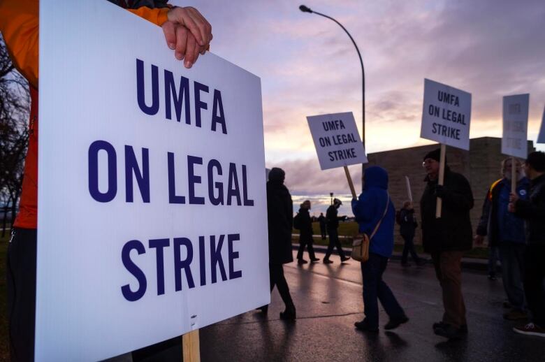 Picketers hold signs saying 