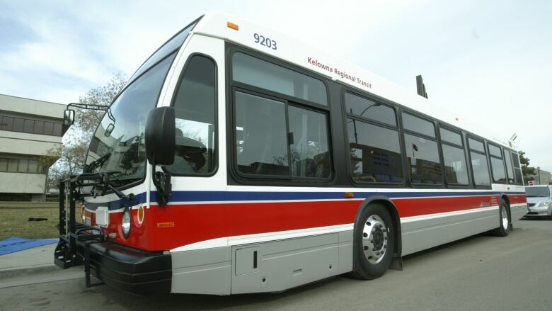 A white transit bus with a red and blue stripe. 