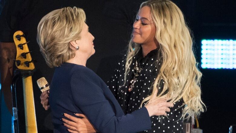 Two women embrace on a stage