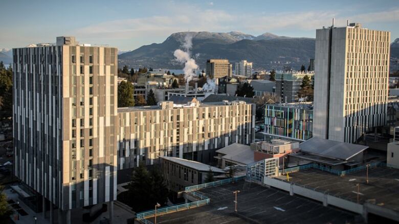 A large grey building with mountains in the background. 