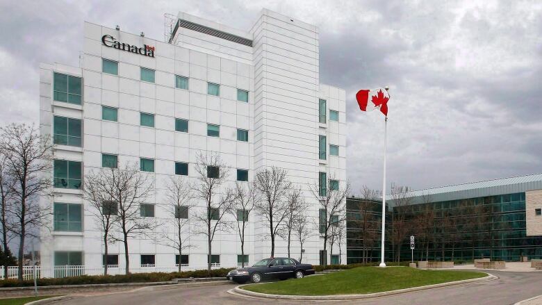 A building with a Canadian flag waving next to it.