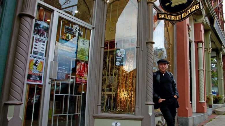 A man leaning against a pole outside a shop