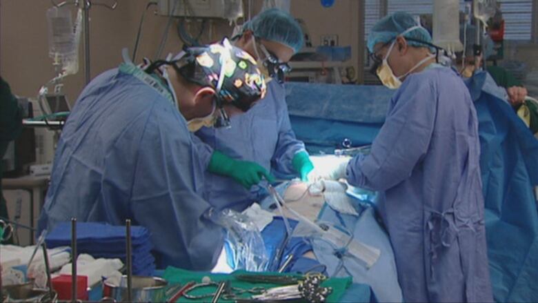 Surgeons in blue scrubs are performing open heart surgery