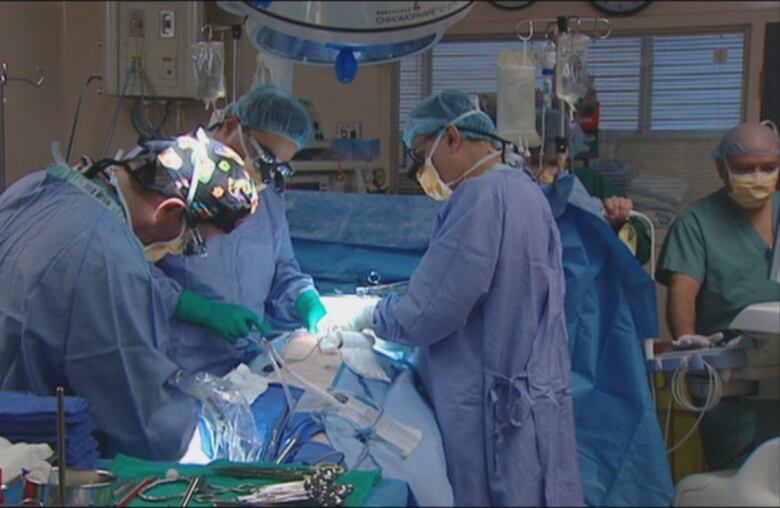 Surgeons in blue scrubs are performing open heart surgery