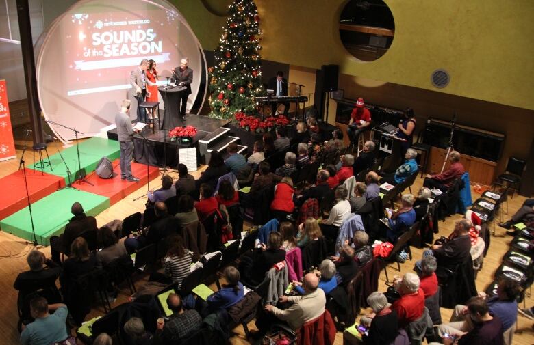 A shot of the seated audience and stage with the words 