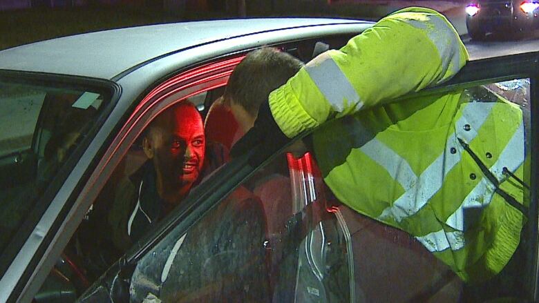 An officer in a fluorescent jacket speaks to a motorist.