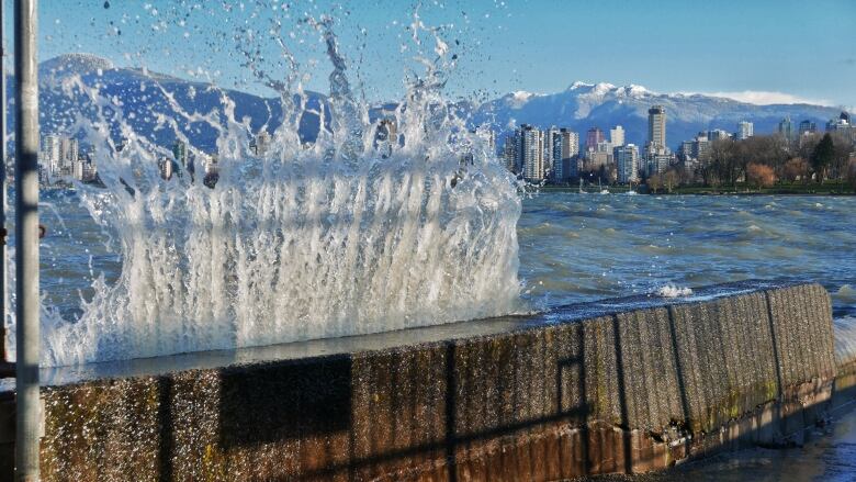 A wave hits a concrete wall at an outdoor pool.