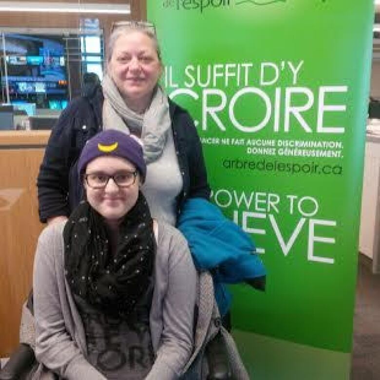 A woman standing behind a teen girl in a wheelchair