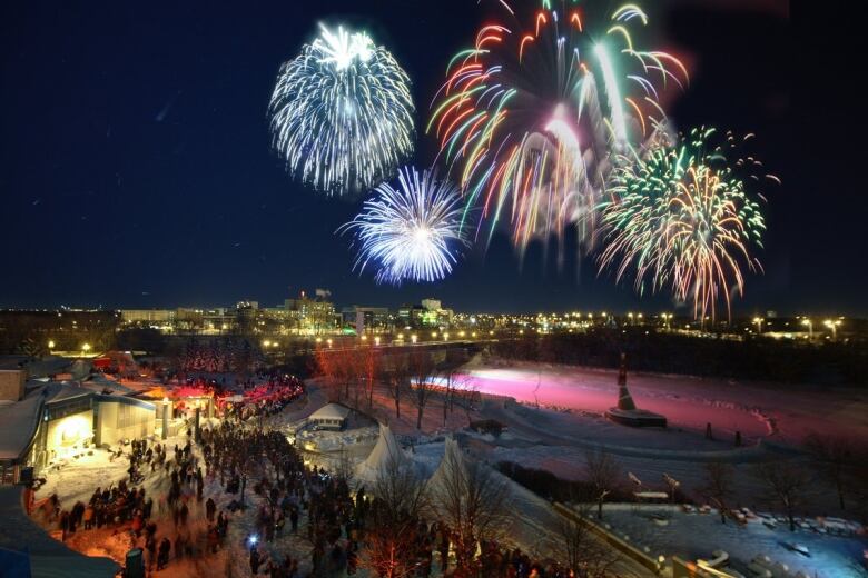 Fireworks explode above city buildings.