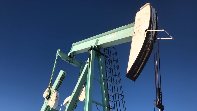 An oil pumpjack stands under a clear blue sky.