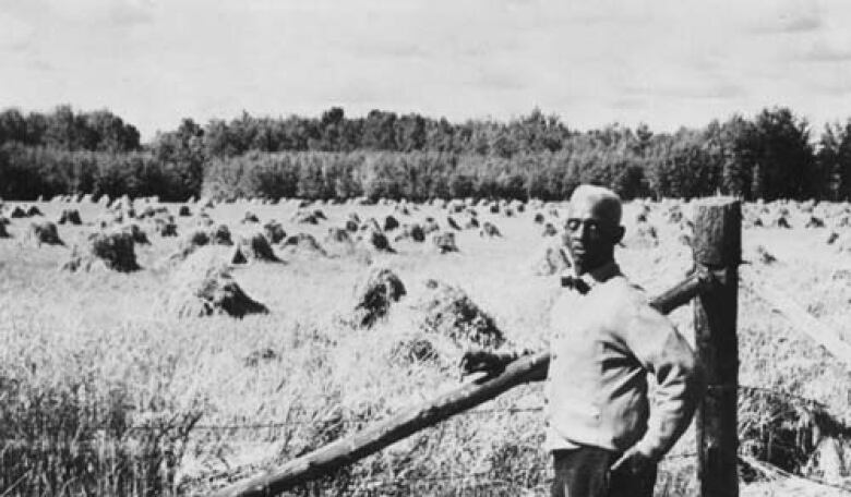 In this photograph from the late 1940's, farmer J. D. Edwards beside grain field, Amber Valley, Alberta.