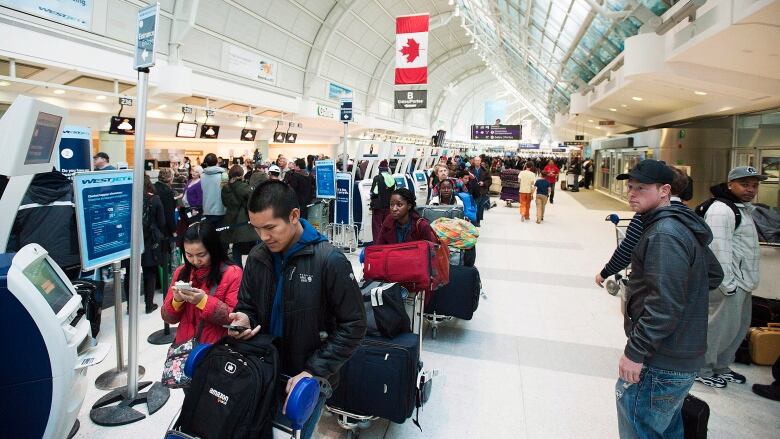 Long shot of travelers waiting in line at Toronto Pearson Airport.