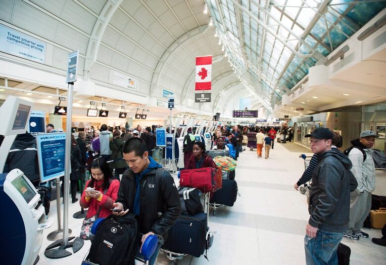 Long shot of travelers waiting in line at Toronto Pearson Airport.