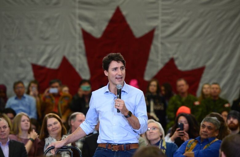 Canadian Prime Minister Justin Trudeau speaks into a microphone at a town hall meeting.