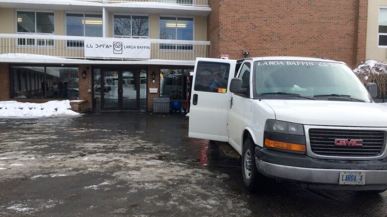 A white van parked outside of a brick building.