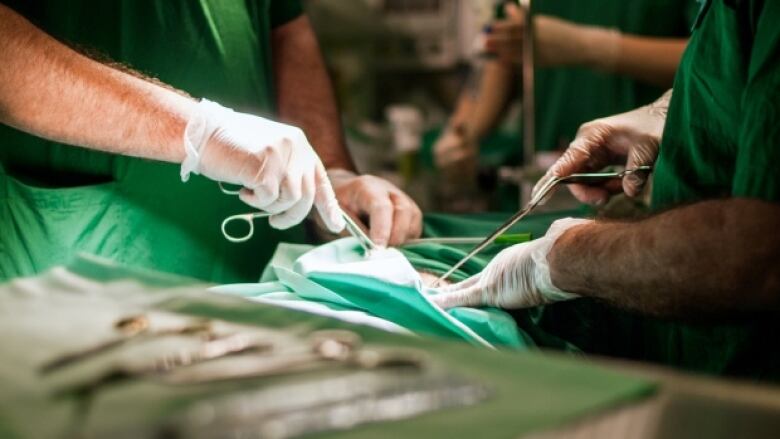 Physicians' hands wield medical instruments during surgery.