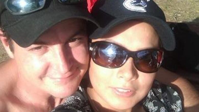 A man with a hat poses with a woman with sunglasses for a selfie.