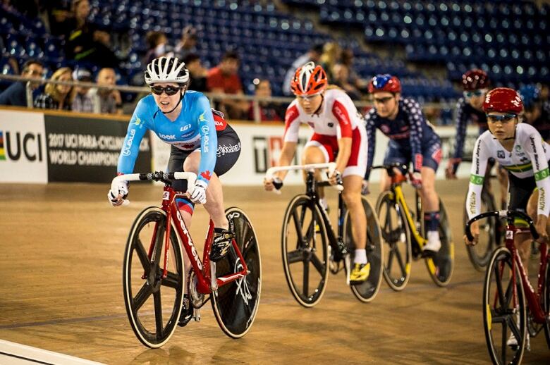 A group of female cyclists on an indoor track.