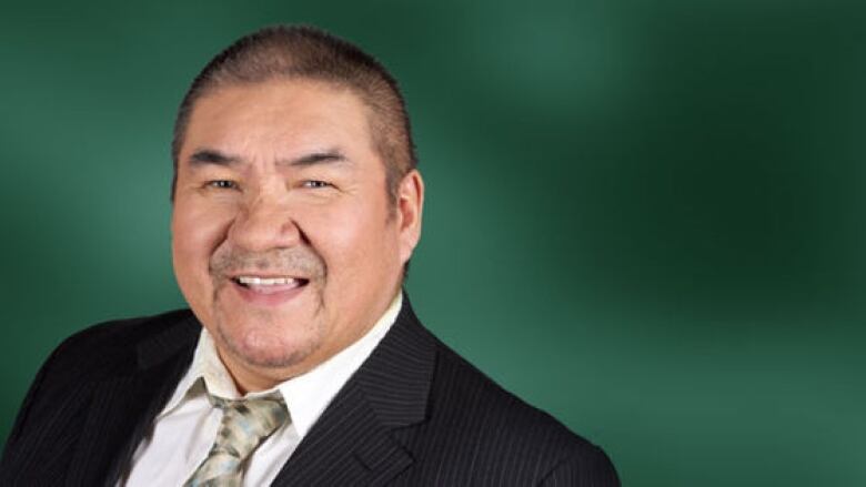 A smiling man with a green tie and a suit.