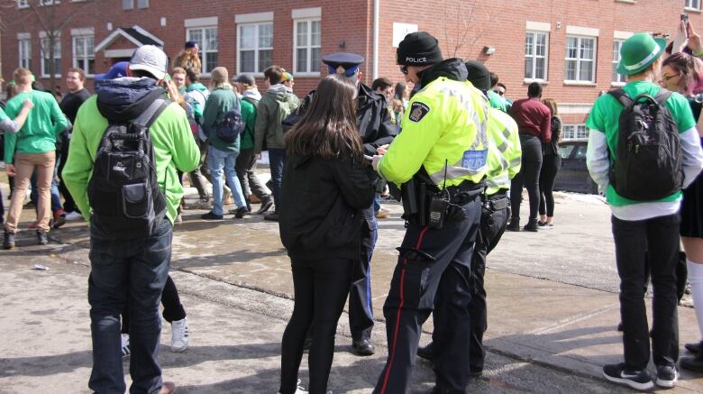 A police officer giving a young woman a ticket on St. Patrick's Day.