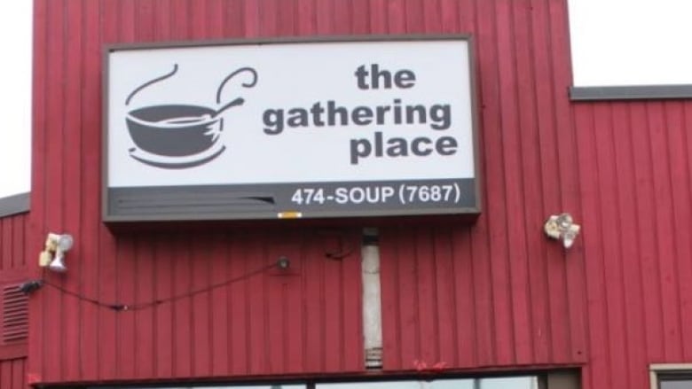 A red building with a black and white sign on it that reads 'the gathering place' 