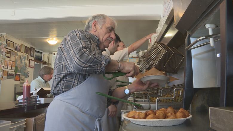 Fotis Fatouros scoops food out of a deep fryer at Pleasant St. Diner.