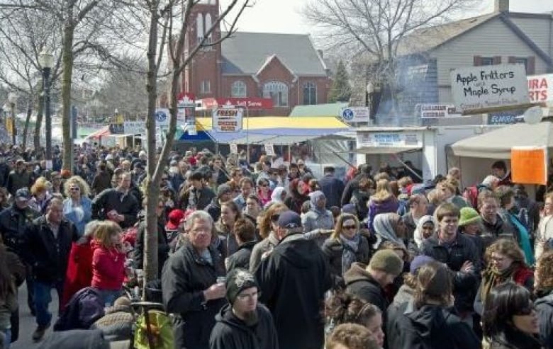 Crowd of people outside. Vendors under small tents are visible.