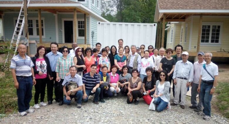 A group of people stand infront of houses under construction.