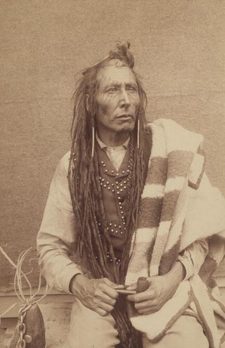 A archive's photo of Chief Poundmaker dressed in a back vest with a blanket over his shoulder.