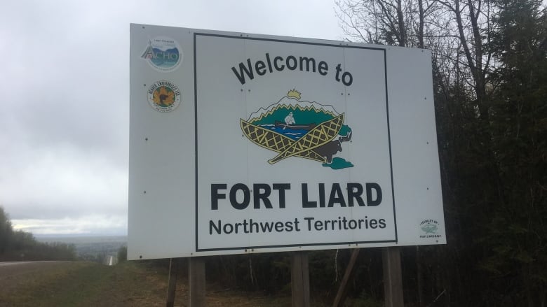 A white sign along a highway on a grey day. 