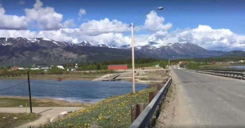 A view up a road toward a village and mountains.