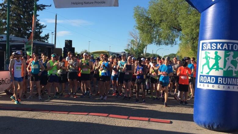 A line of runners stand beneath an inflatable arch as they prepare to begin the marathon.