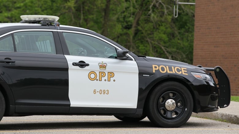 An OPP cruiser parked outside a brick building.