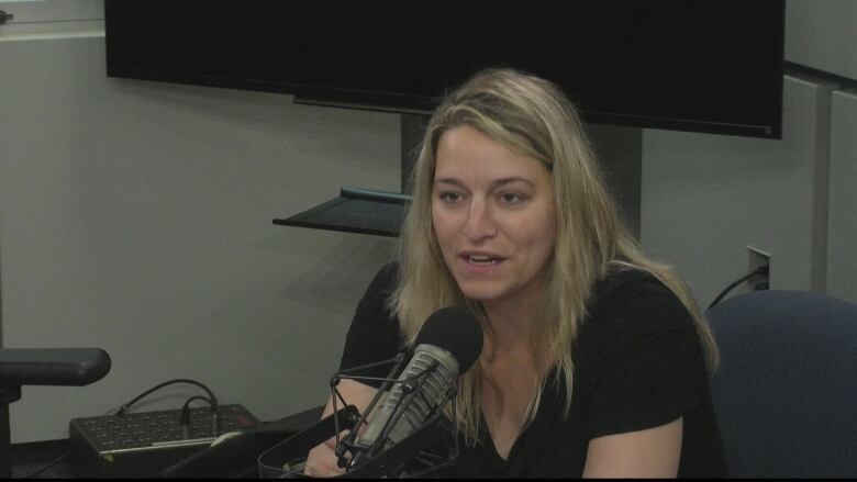 A woman sits in front of a microphone.