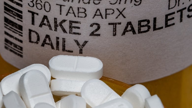 A pill bottle with a handful of pills in front of it.