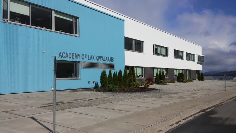 A new looking blue, white and grey school building with a sign reading 